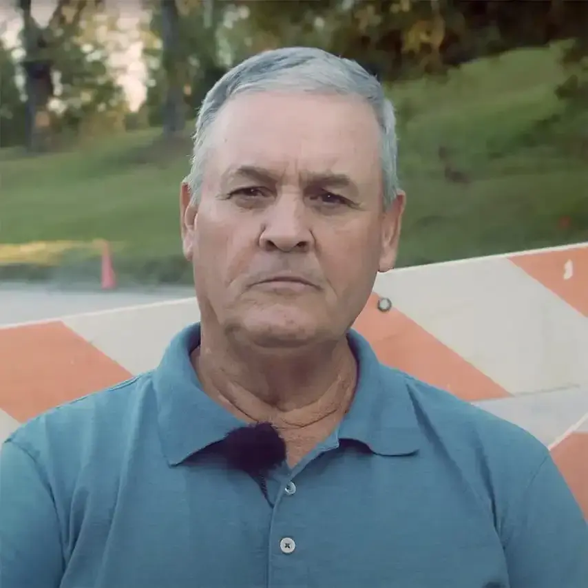 Garry Doggett in a polo shirt in front of a road-work barricade