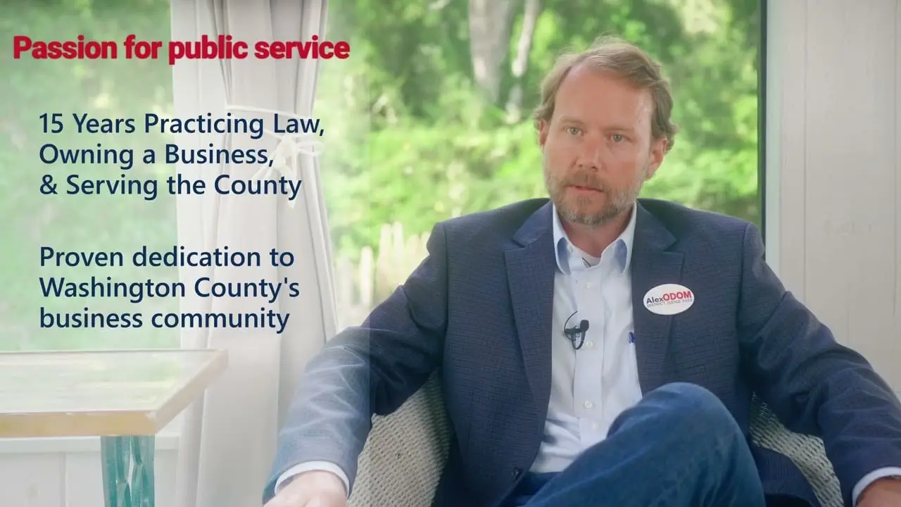 Alex Odom sits by a window beside on-screen text about 15 years practicing law, owning a business, and serving the county, from a campaign video AVO Dynamics made for Alex Odom's 2022 run for District Judge